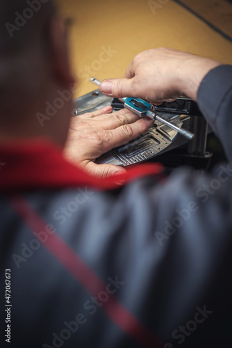 A heavy industrial worker in a factory works with metal on angle grinders while hot sparks are produced as a result.