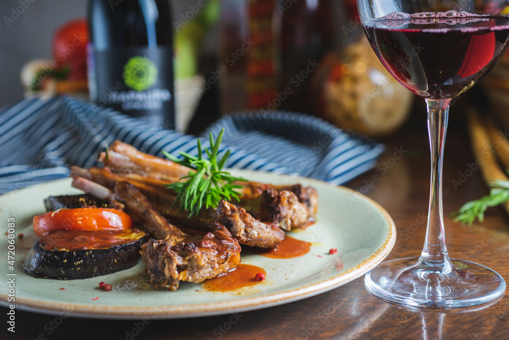Fried ribs with a glass of red wine on a table in a restaurant close-up Fried ribs with a glass of red wine on a table in a restaurant close-up