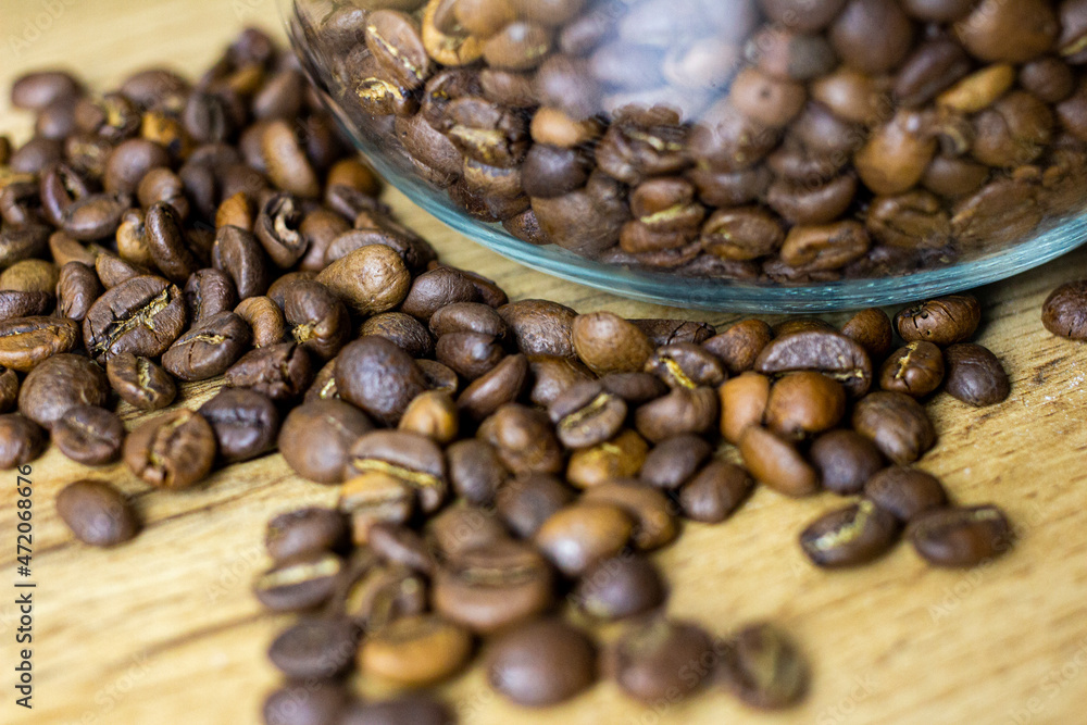 Roasted coffee beans in glass can on wooden table Roasted coffee beans in glass can on wooden table