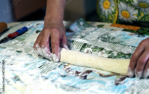 Woman in the kitchen kneads dough, close up photo. Healthy homemade food concept.