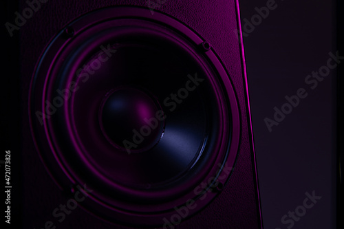 large speaker close-up on a black background with violet-purple illumination close-up  music playback on a luxury speaker system