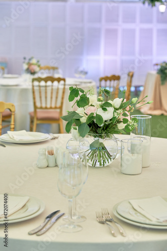 Beautiful floral arrangement of rose flowers and greenery on wedding table in restaurant, copy space. Luxury wedding decorations. Table setting