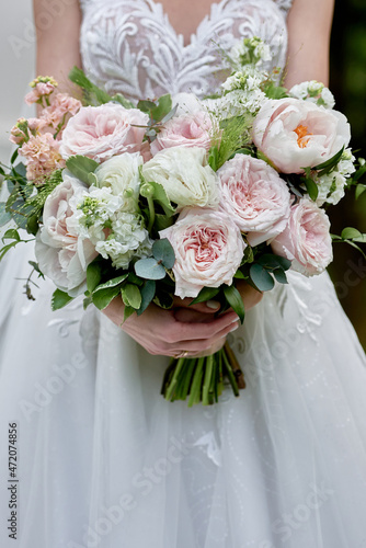 Portrait of beautiful bride in wedding dress with bridal bouquet of white and pink rose flowers outdoors, copy space. Wedding concept