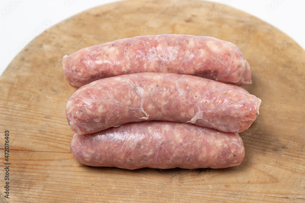 Raw meat sausages on a wooden board on a white background. Homemade sausages in a natural casing. Meat products Raw meat sausages on a wooden board on a white background. Homemade sausages in a natural casing. Meat products