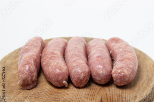 Raw meat sausages on a wooden board on a white background. Homemade sausages in a natural casing. Meat products