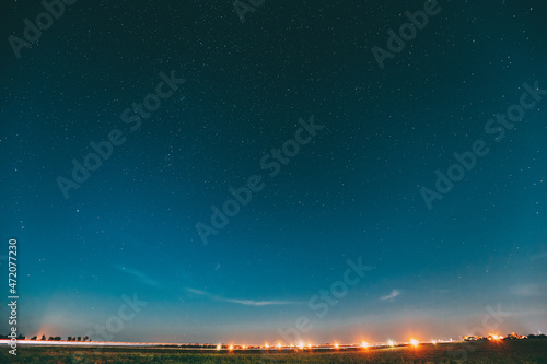 Night Starry Sky With Glowing Stars Above Landscape With City Lights. Night Starry Sky Above Ground. Copy Space