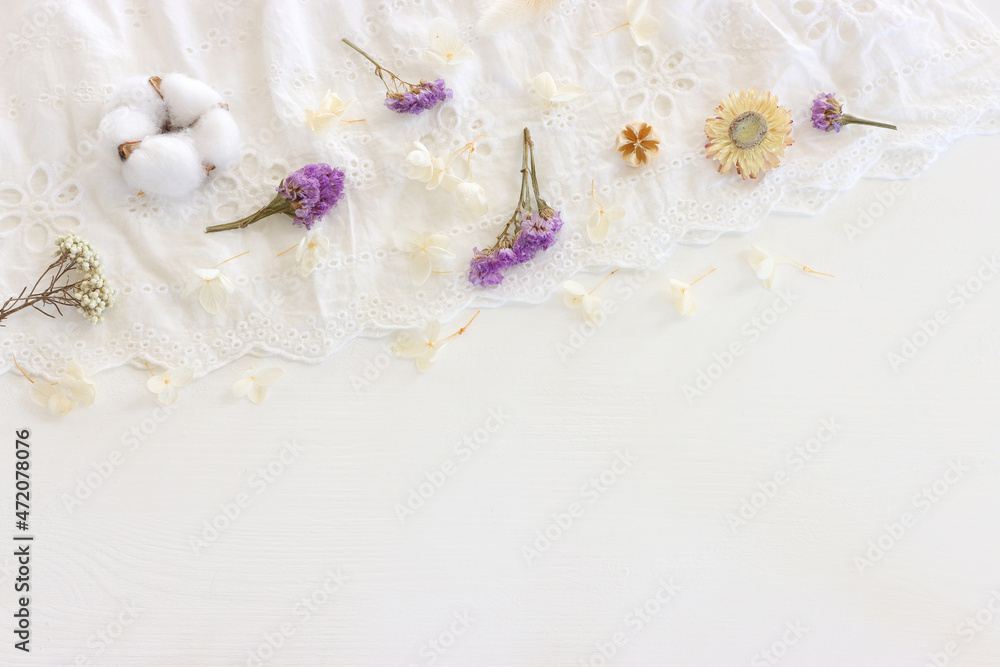 Background of white embroidered delicate lace fabric and dry flowers - obrazy, fototapety, plakaty 