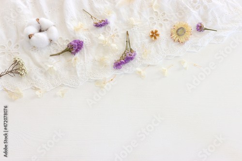 Background of white embroidered delicate lace fabric and dry flowers