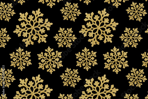 Seamless pattern. Golden snowflakes on a black background