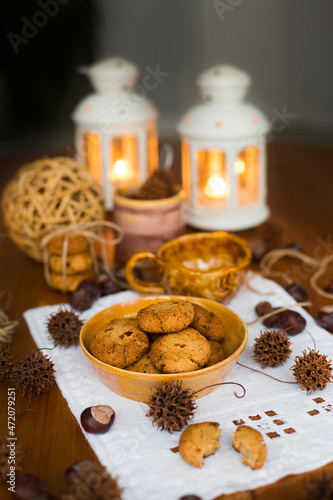  Homemade oatmeal cookies in yellow clay plate on white embroidered napkin against the background of candlesticks
