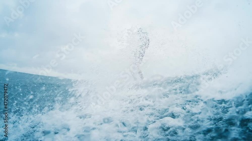 Surfer rides the wave. Man in red wetsuit surfs the wave during rainy day. Stylish male longboarder with long hair surfs the wave in rain (Egor Selyanko) photo