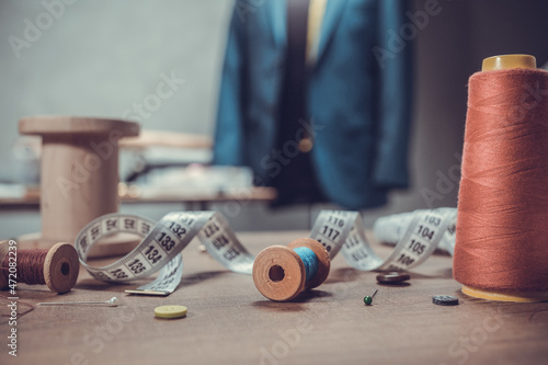 Thread spool and tape measure with sewing tools on table. Concept of clothes atelier workplace