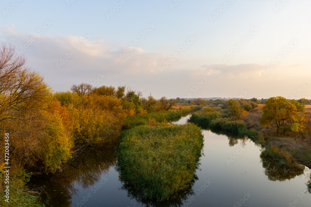 autumn landscape with a view of the river at sunset. Trees along the banks with colorful leaves