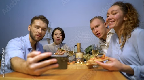happy friends eating pizza together, four young students enjoying a festive lunch meeting time sitting at the table and video chatting on smartphones New normal lifestyle, social distancing concept photo