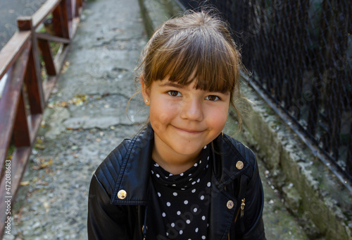 Smiling cute brown hair school girl in polka dot dress and leather jacket