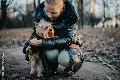 young woman with Yorkshire terrier dog on a walk in winter. © velimir
