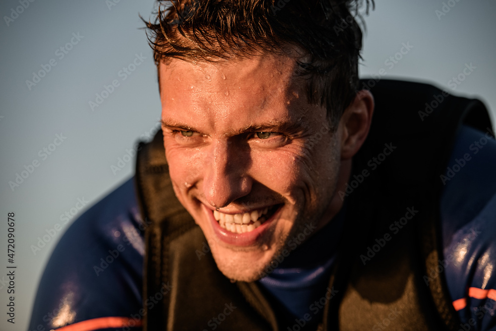Close-up view of face of cheerful athletic man in wetsuit and vest Close-up view of face of cheerful athletic man in wetsuit and vest