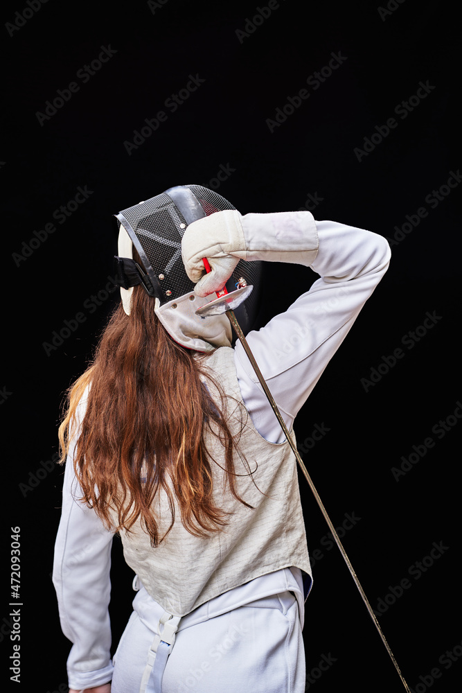 Portrait of woman dressed in white fencing costume practicing with the sword on black background. Portrait of woman dressed in white fencing costume practicing with the sword on black background.