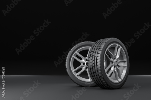 Four car tires stacked on a black background