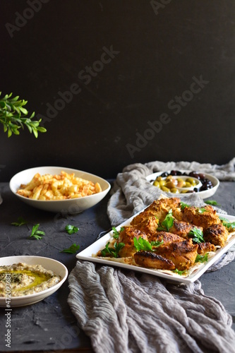 Grilled and smoked Turkish chicken with sauce, appetizers and french fries, garnished with parsley on an isolated black background