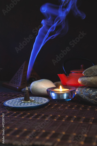 Incienso encendido con humo azul en un fondo oscuro