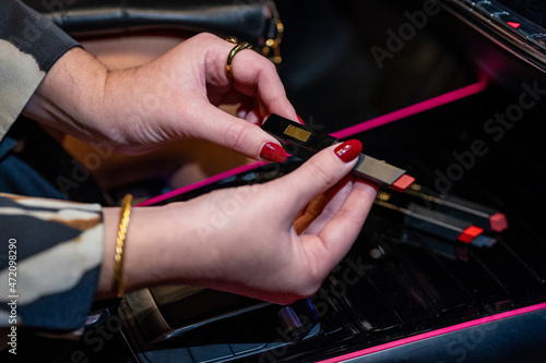 woman's hands holding lipstick stick inside a car