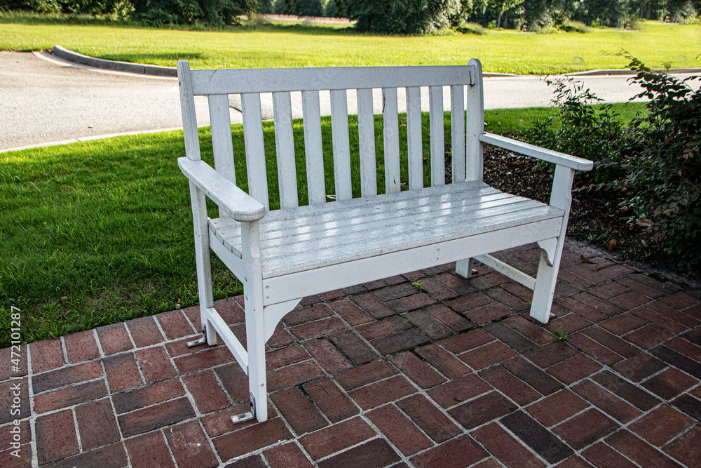 A white wooden park bench in a park A white wooden park bench in a park