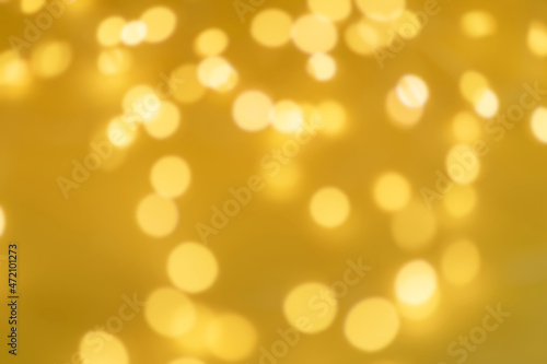Defocused yellow background. Festive Christmas background from a glowing garland with many lights. New Years celebration concept.