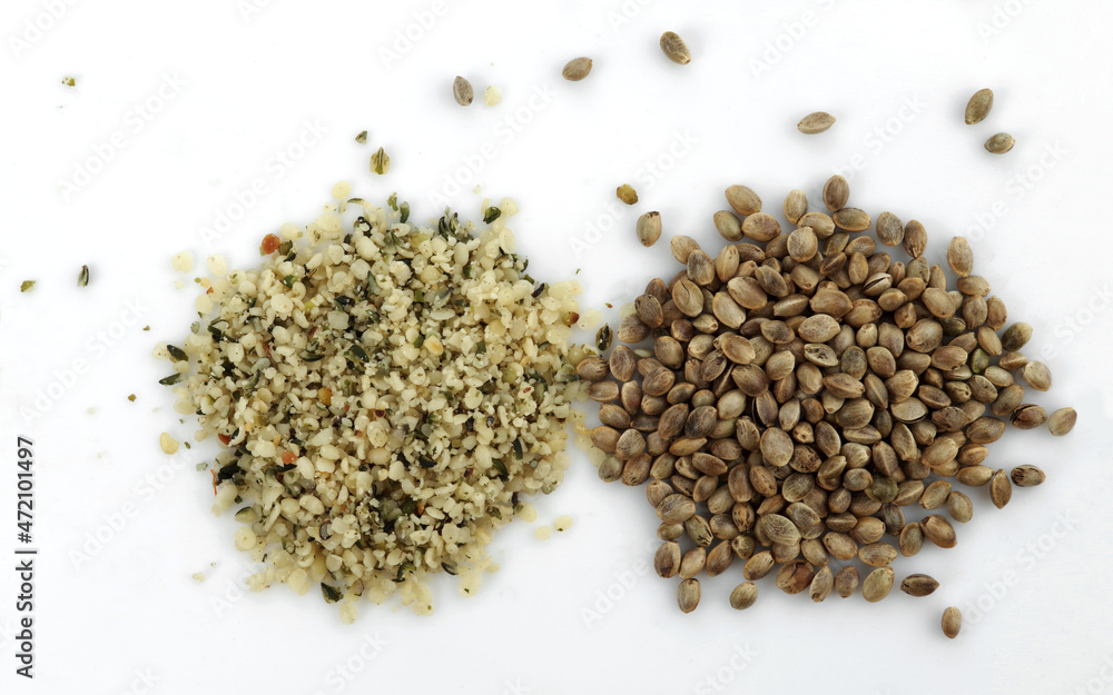 Two heaps of raw hemp seeds, whole and shelled, on a white background. Two heaps of raw hemp seeds, whole and shelled, on a white background.