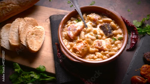 Traditional recipe of beans with chorizo and blood sausage called “Fabada Asturiana” on a dark table with some ingredients around. Typical Spanish food with “compango”. 