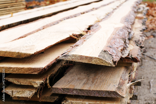 A stack of fresh unedged boards from a pine trunk in a sawmill warehouse. Harvesting, sale of lumber for construction photo