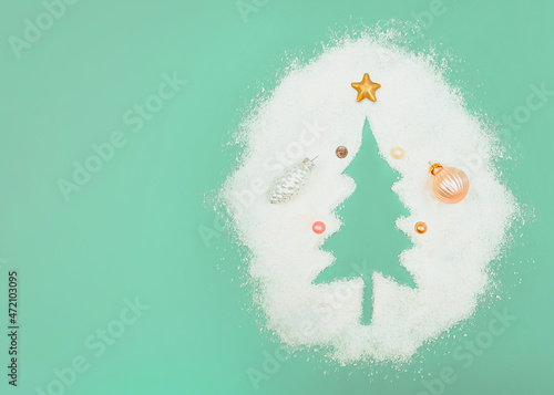 Pastel mint concept. Christmas tree silhouette. with copy space. New Year's decorations in caramel and pastel color. Pearl white silver cone. Small balls and a copper Christmas star. Blown snow. photo