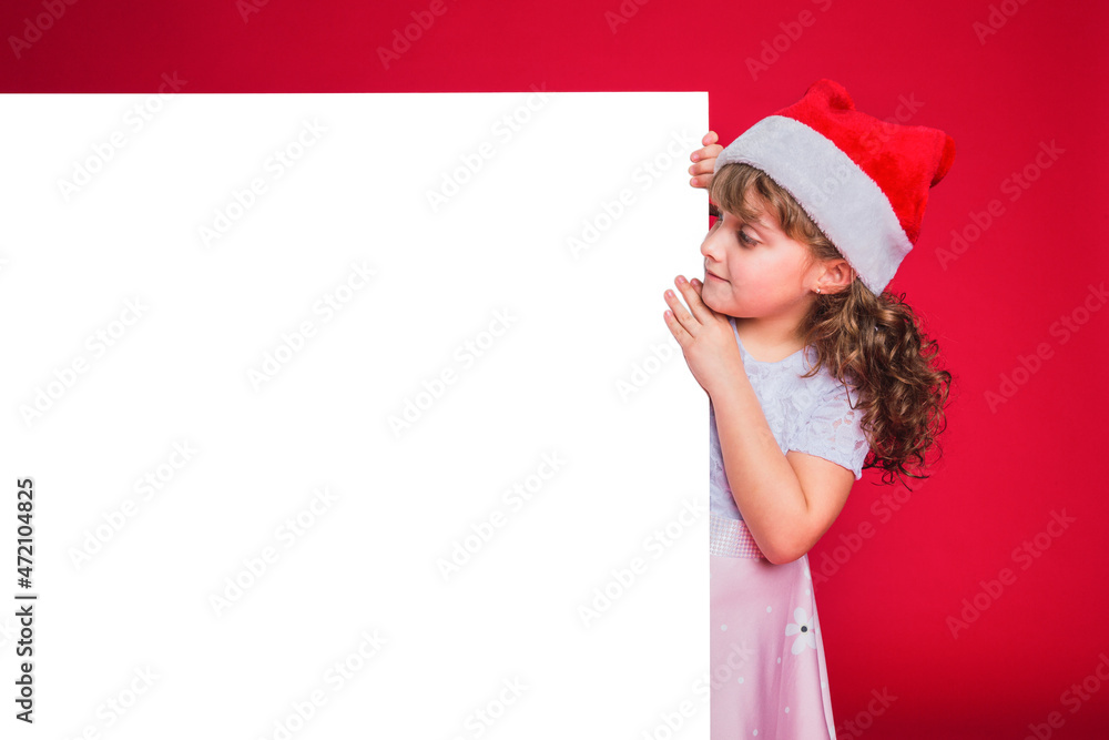 Little girl with red Santa Claus hat holding a billboard. Little girl with red Santa Claus hat holding a billboard.