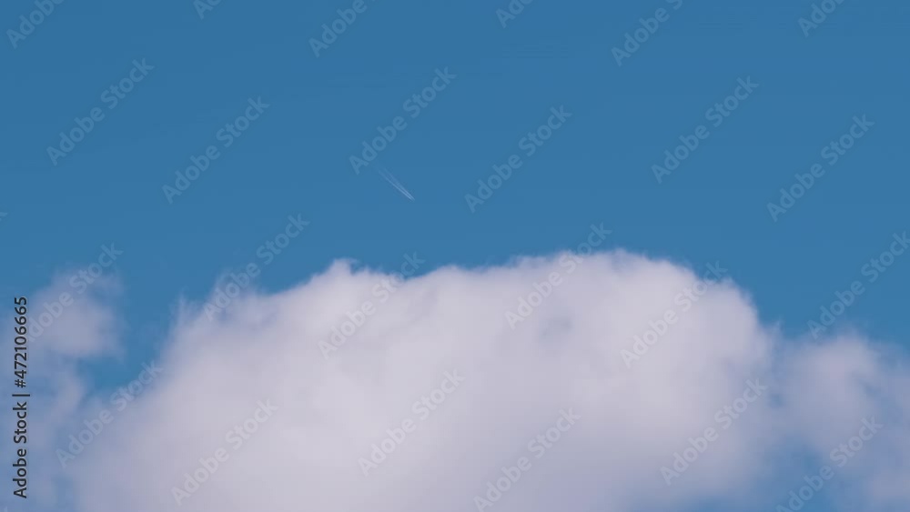 Distant passenger jet plane flying on high altitude on blue sky with white clouds leaving smoke trace of contrail behind. Air traveling concept. Distant passenger jet plane flying on high altitude on blue sky with white clouds leaving smoke trace of contrail behind. Air traveling concept.