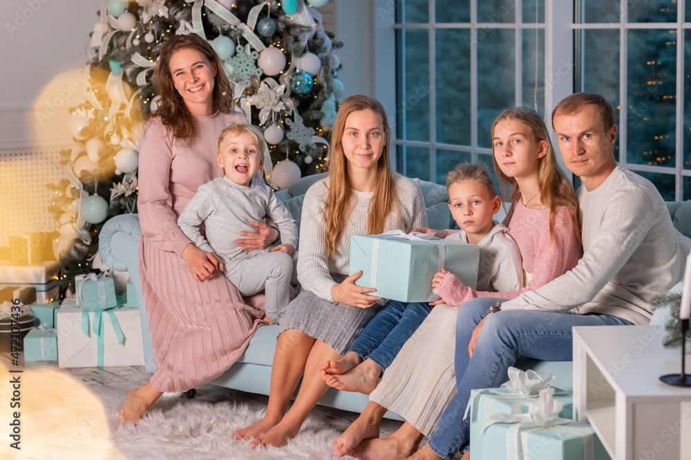 Big happy family with many kids having fun on the sofa near the Christmas tree on Christmas eve