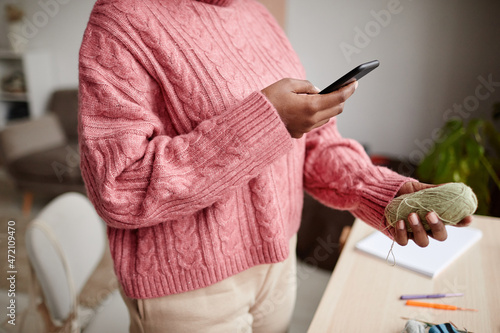 Cropped portrait of young African-American woman taking photo of knitting wool  copy space
