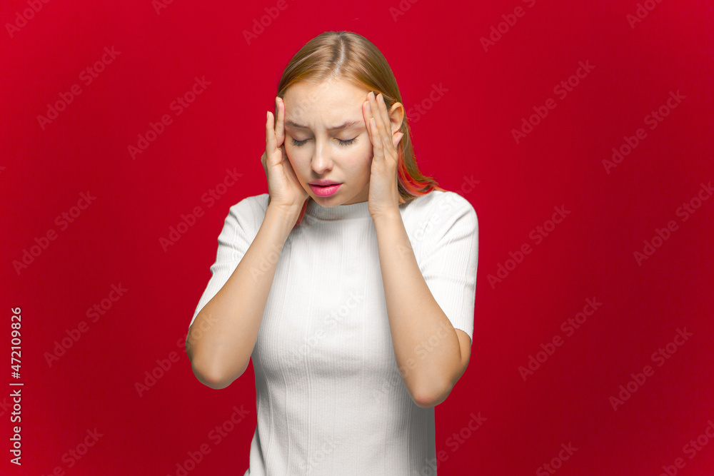 Anxiety and migraine. Ill young girl massaging temples suffer headache, closed eyes from strong pain on red background Anxiety and migraine. Ill young girl massaging temples suffer headache, closed eyes from strong pain on red background