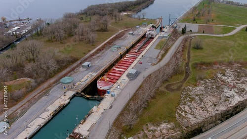 A self discharging bulk carrier ship prepares to cross the locks of the Beauharnois Canal in the St Lawrence Seaway, near Montreal, Quebec. High quality 4K aerial view. photo