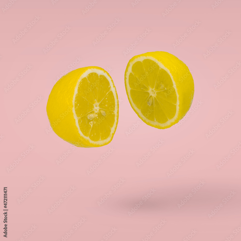 Juicy lemon cut in two halves flying in the air on a pasel pink background. Summer citrus fruit refreshment. Juicy lemon cut in two halves flying in the air on a pasel pink background. Summer citrus fruit refreshment.