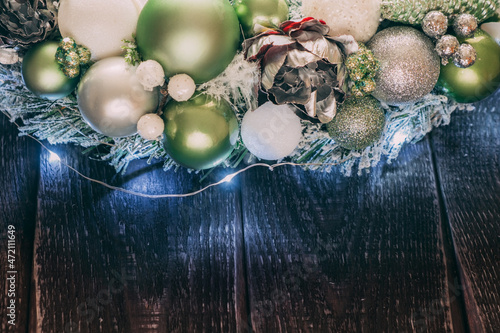 Part of a handmade Christmas wreath on a dark wooden background from boards. The wreath is highlighted with garlands and is located at the top of the frame. Copy space. © AndreyFrol