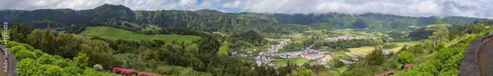 Huge panorama landscape of natural place full of trees, mountains and small remote village in country side of sao miguel island, azores, açores