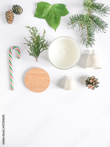 Merry season with aromatic candle, white bells, candy, pine cones, green leave and fir branch on the white background. 