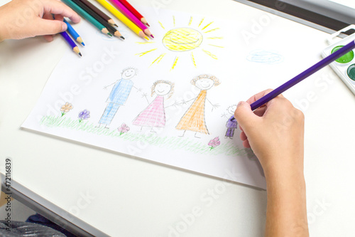 The concept of a happy childhood and a big friendly family. The child depicts a portrait of a family.