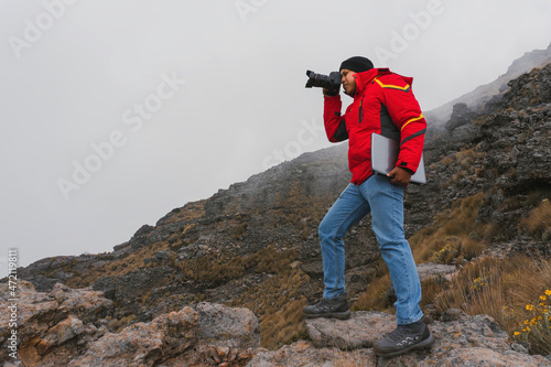 travel photographer with camera and laptop in the mountains