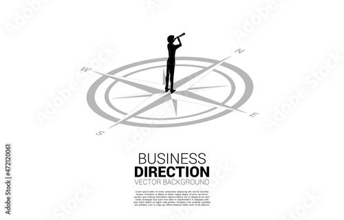 Silhouette of businessman looking through telescope on center of compass on floor. Concept of career path and business direction