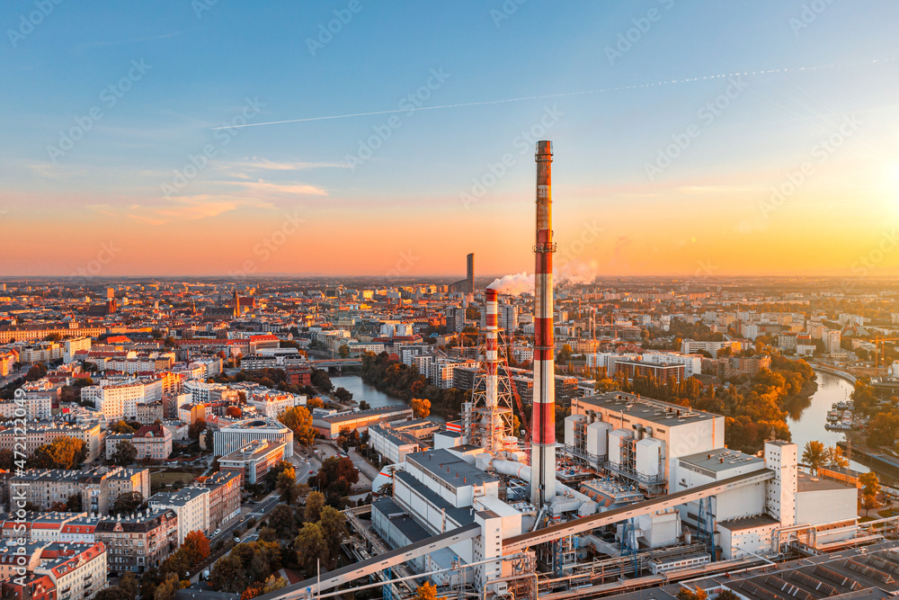 Fototapeta premium City CHP, power plant with smoking chimneys against the background of the city, aerial photography. Air pollution concept from factories
