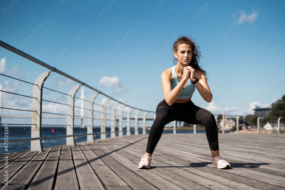 Woman running city embankment, athletic figure, comfortable fitness clothes. A sporty lifestyle, the coach does physical exercises.