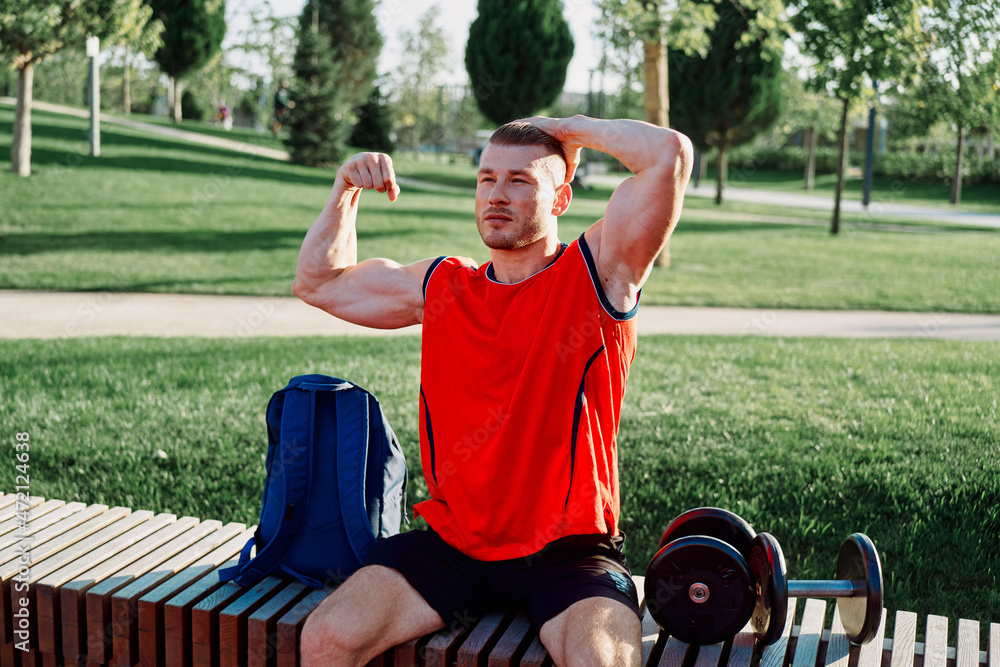 Cheerful male athlete in the park sits on a bench Cheerful male athlete in the park sits on a bench