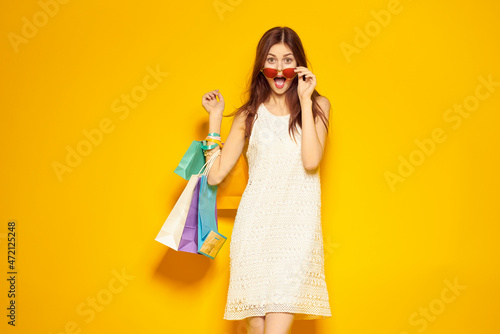 cheerful woman with packages in hands Shopaholic yellow background