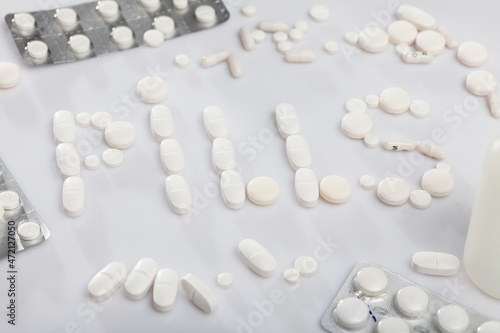 Various tablets and capsules formed word PILLS on white background. Medical prescription concept